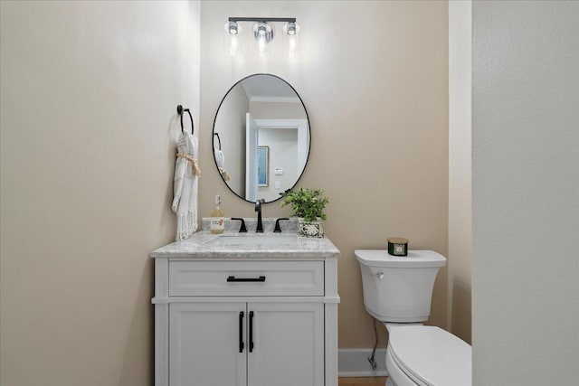 bathroom featuring toilet, vanity, and baseboards