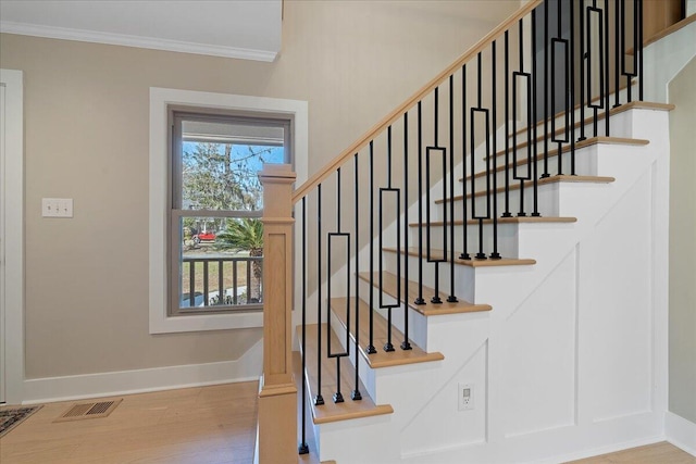 stairway with visible vents, crown molding, baseboards, and wood finished floors