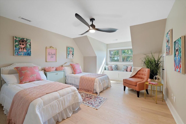 bedroom with visible vents, light wood-style floors, baseboards, ceiling fan, and vaulted ceiling