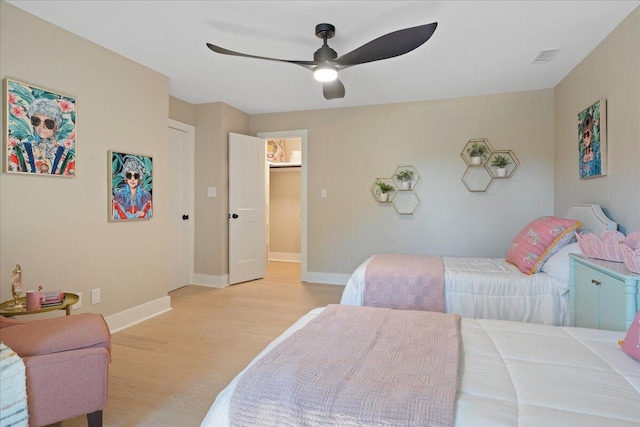 bedroom with light wood-style flooring, visible vents, baseboards, and ceiling fan