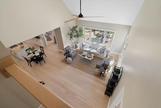 living area with baseboards, high vaulted ceiling, ceiling fan, and wood finished floors