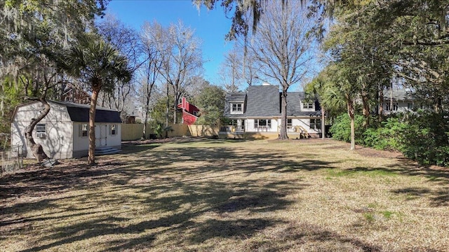 view of yard with a wooden deck, an outdoor structure, and fence