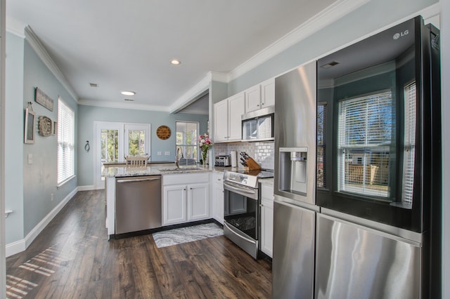 kitchen featuring a peninsula, appliances with stainless steel finishes, white cabinets, and a sink