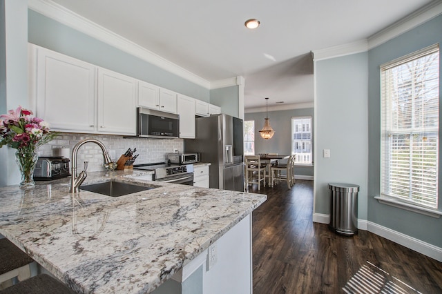 kitchen featuring light stone counters, stainless steel appliances, a sink, and ornamental molding