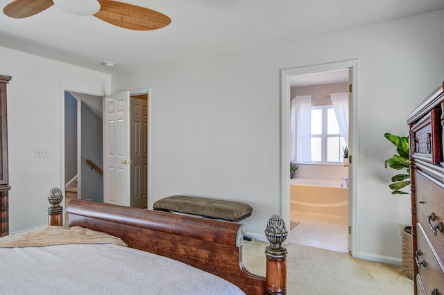 bedroom with baseboards, light colored carpet, and ensuite bath