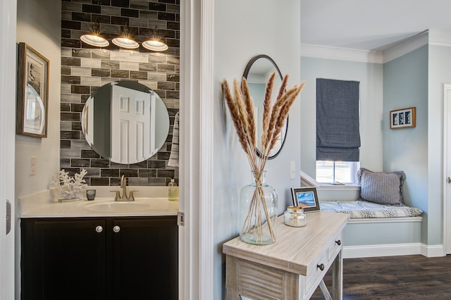 bathroom with tasteful backsplash, ornamental molding, vanity, wood finished floors, and baseboards