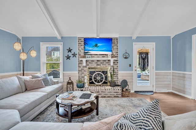 living area with visible vents, lofted ceiling with beams, wood finished floors, wainscoting, and a fireplace