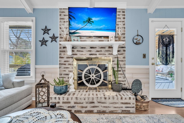 living room with beamed ceiling, a fireplace, wood finished floors, and crown molding