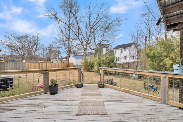 wooden terrace with central air condition unit, a fenced backyard, and a residential view