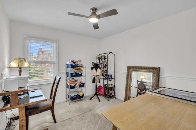 office featuring a ceiling fan, baseboards, and light carpet