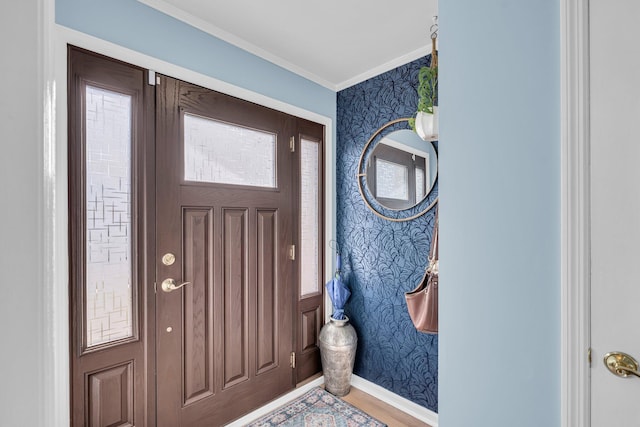 foyer with baseboards, wood finished floors, crown molding, and wallpapered walls