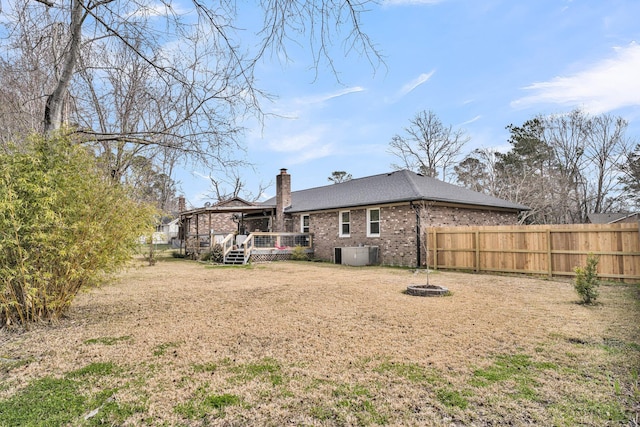 rear view of house with cooling unit, fence, a chimney, a deck, and brick siding