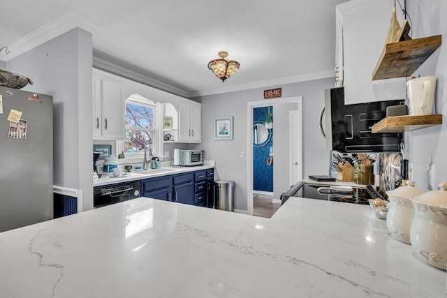 kitchen with blue cabinetry, a sink, white cabinetry, freestanding refrigerator, and crown molding