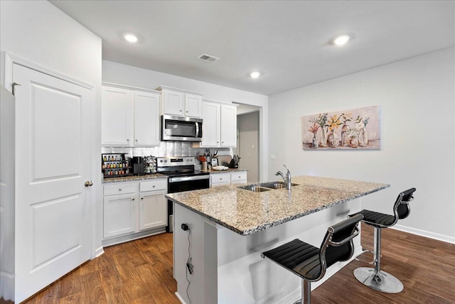 kitchen featuring a kitchen bar, white cabinetry, stainless steel appliances, an island with sink, and sink