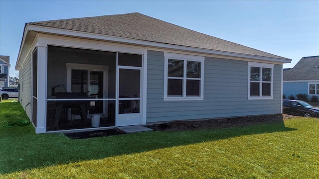 rear view of house featuring a yard and a sunroom