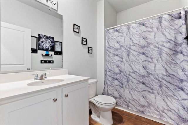 bathroom with toilet, hardwood / wood-style flooring, vanity, and curtained shower