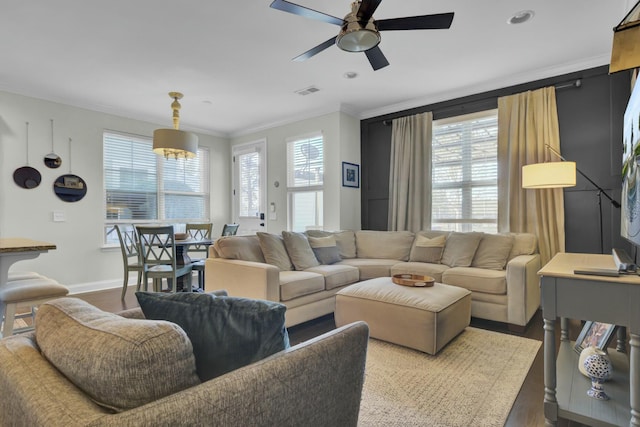 living room featuring wood finished floors, a ceiling fan, visible vents, and a wealth of natural light