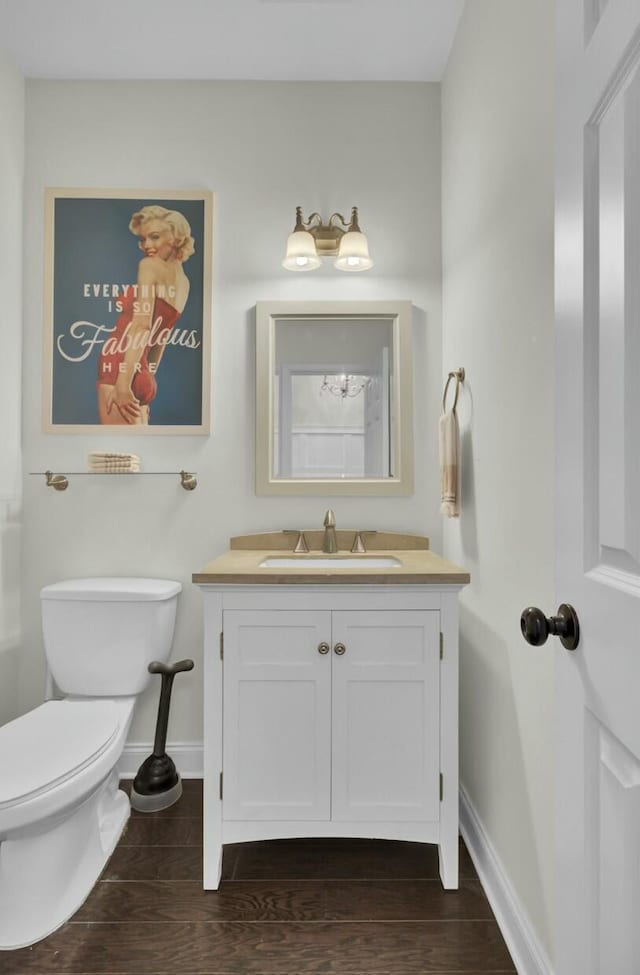 bathroom with baseboards, toilet, wood finished floors, and vanity