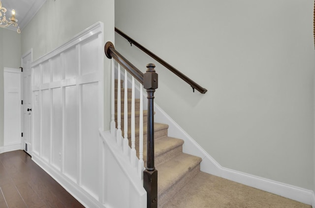 stairway featuring baseboards, crown molding, an inviting chandelier, and wood finished floors