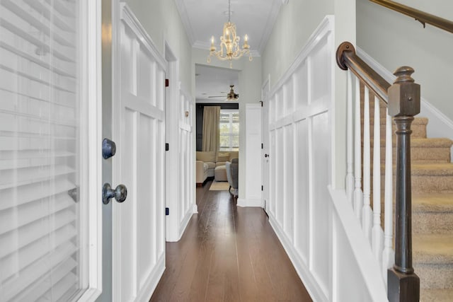 hall featuring stairway, an inviting chandelier, dark wood finished floors, and crown molding