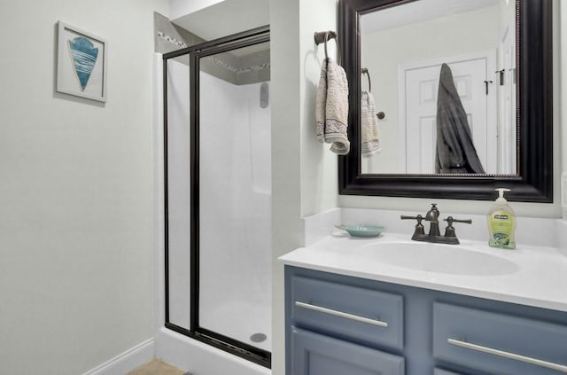 full bathroom featuring a stall shower, vanity, and baseboards