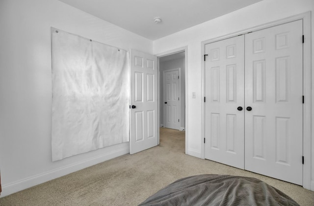 carpeted bedroom with baseboards and a closet