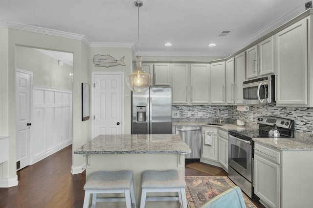 kitchen with dark wood finished floors, ornamental molding, decorative backsplash, stainless steel appliances, and a sink