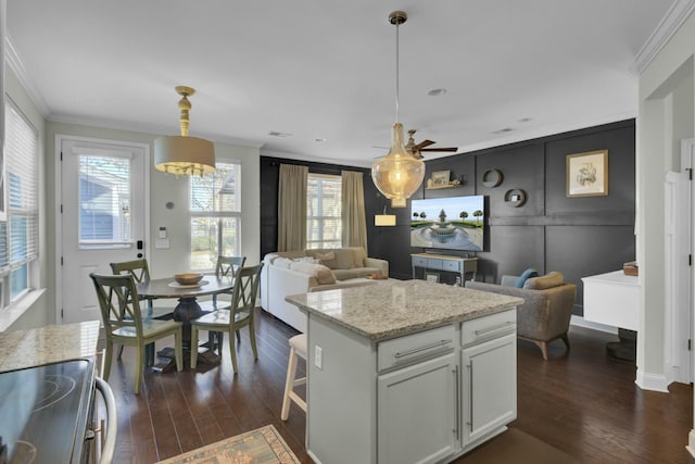 kitchen featuring hanging light fixtures, open floor plan, dark wood-type flooring, and ornamental molding