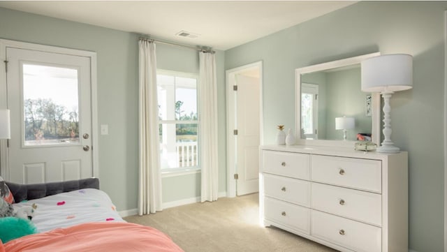bedroom featuring light carpet, multiple windows, and baseboards