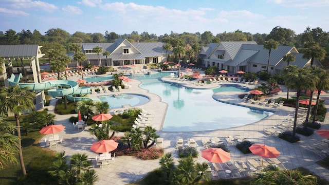 community pool featuring a water slide, a patio area, and view of scattered trees
