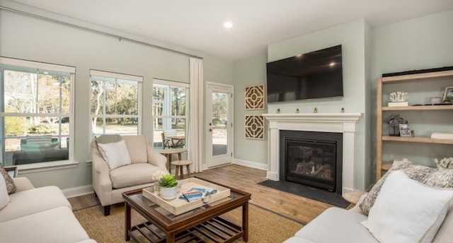 living area with wood finished floors, a fireplace with flush hearth, baseboards, and recessed lighting