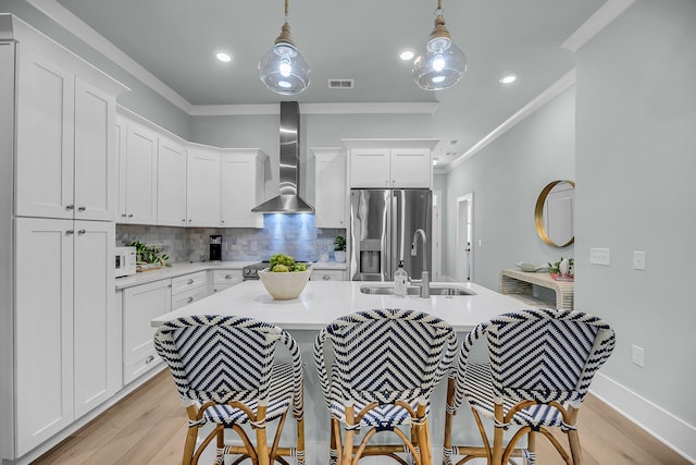 7416 Indigo Palms Way, Johns Island, SC 29455 - kitchen with wall chimney range hood, stainless steel fridge with ice dispenser, a sink, crown molding, and light countertops
