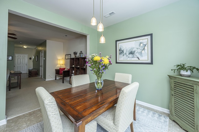 dining space with ceiling fan and light carpet