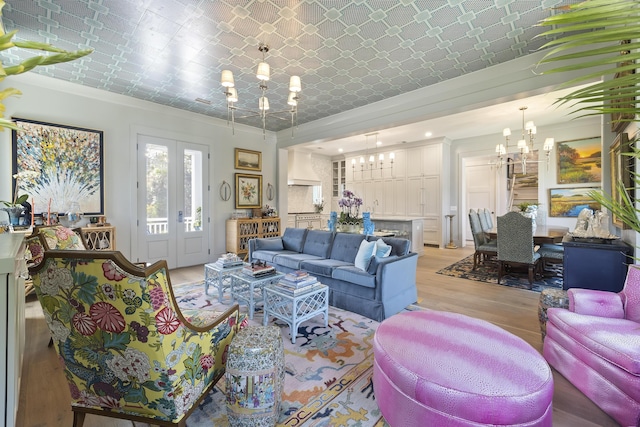 living room featuring an ornate ceiling, a notable chandelier, french doors, and light wood-style floors