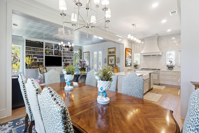 dining space featuring visible vents, light wood-style flooring, a notable chandelier, and a healthy amount of sunlight