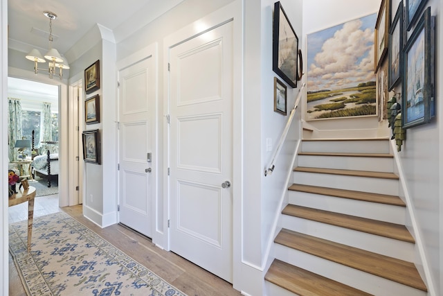 stairs featuring wood finished floors and a notable chandelier