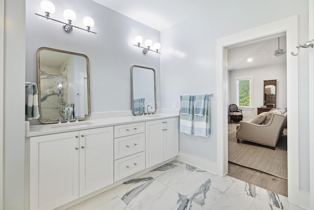 full bath featuring connected bathroom, double vanity, a sink, and marble finish floor