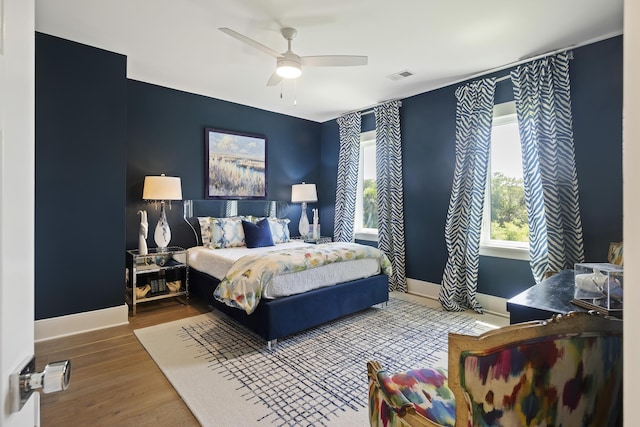 bedroom with a ceiling fan, baseboards, visible vents, and wood finished floors