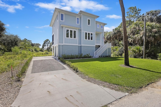 exterior space with a lawn, board and batten siding, aphalt driveway, and stairway