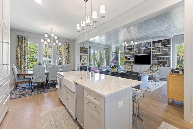 kitchen with a sink, white cabinets, a notable chandelier, and hardwood / wood-style flooring