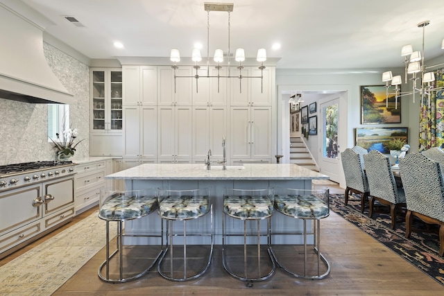 kitchen featuring a kitchen breakfast bar, light stone countertops, visible vents, and custom exhaust hood