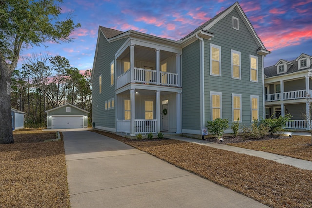 view of front of property with covered porch, a detached garage, an outbuilding, and a balcony