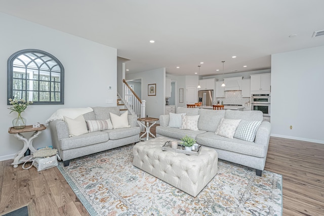 living room with stairs, light wood finished floors, baseboards, and recessed lighting