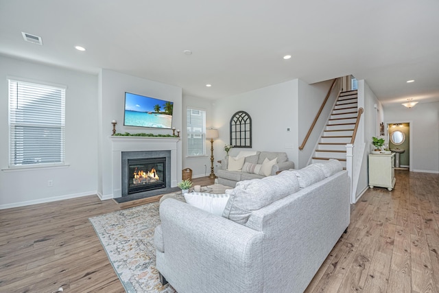 living area featuring recessed lighting, light wood-style flooring, and a glass covered fireplace