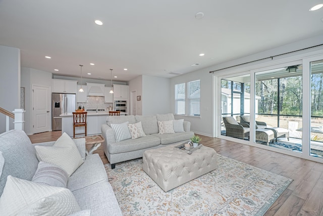 living area with stairway, recessed lighting, and light wood-style flooring