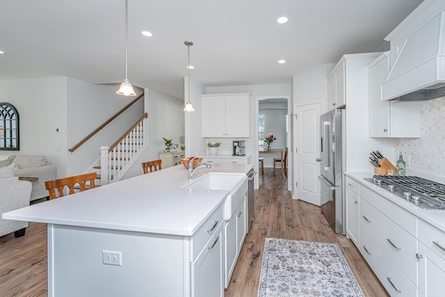 kitchen featuring appliances with stainless steel finishes, light wood-type flooring, light countertops, and custom range hood