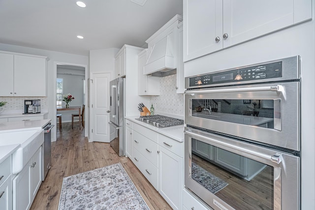 kitchen featuring white cabinets, light wood finished floors, stainless steel appliances, and light countertops