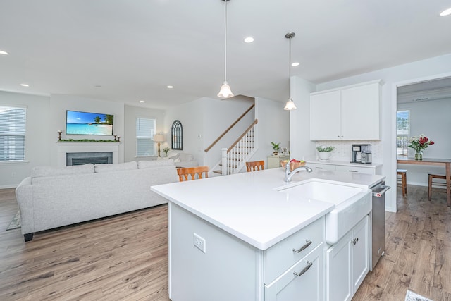 kitchen with a fireplace, light wood-style floors, open floor plan, hanging light fixtures, and light countertops