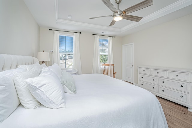 bedroom with a tray ceiling, wood finished floors, and ornamental molding