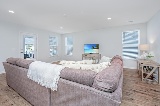 living area featuring baseboards, light wood finished floors, visible vents, and a healthy amount of sunlight